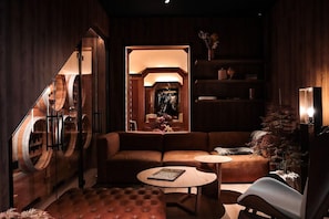 A cozy, dimly lit room with a leather sofa, a round coffee table, and a bookshelf. - Villars Palace (Ollon)