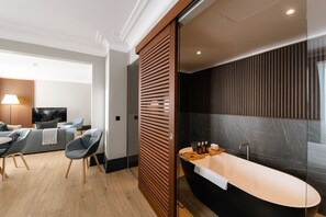 A modern bathroom with a freestanding bathtub, a vanity with a mirror, and a shower area.