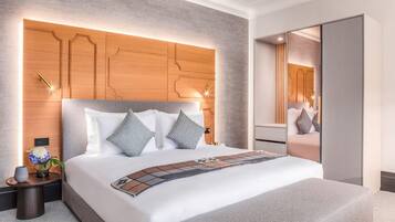 Ein modernes Hotelzimmer mit einem großen Bett, einem hölzernen Kopfteil, einem Nachttisch mit einer Vase und einem Spiegel.