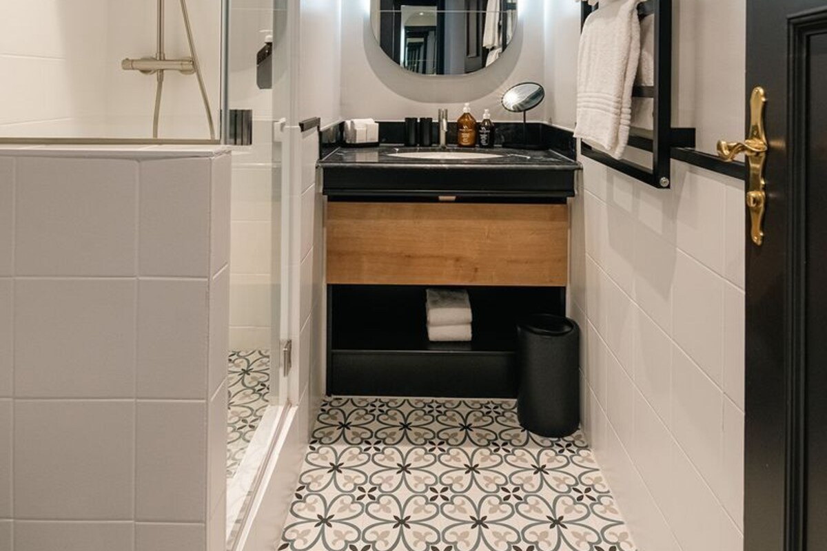 Une salle de bain moderne avec une douche, un lavabo avec un miroir et un carrelage décoratif.