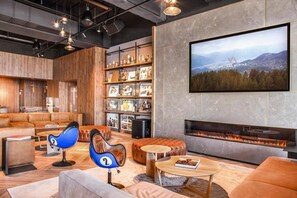 A modern living room with a fireplace, leather sofas, a coffee table, and a bookshelf with framed photos. - Villars Palace (Ollon)