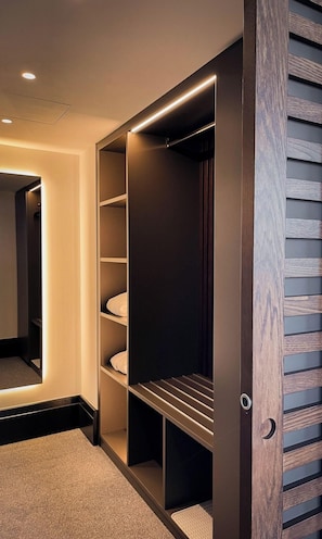 A walk-in closet with built-in lighting, multiple shelves, and a mirrored closet door. - Villars Palace (Ollon)