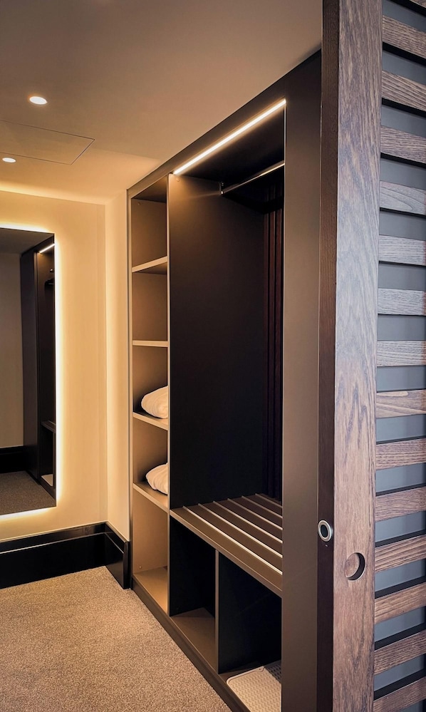 A walk-in closet with built-in lighting, multiple shelves, and a mirrored closet door. - Villars Palace (Ollon)