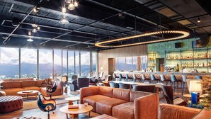 Eine moderne Lounge mit Ledersofas, einer Bar und Blick auf die Berge.