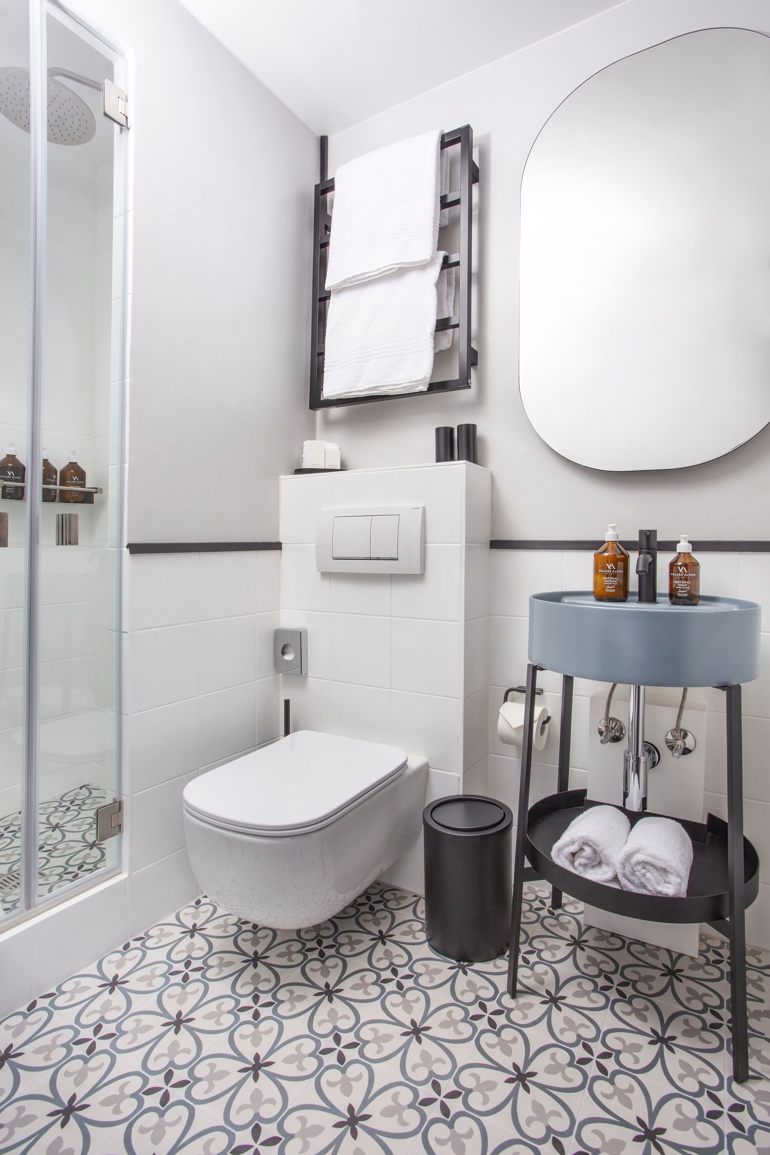 A modern bathroom with a toilet, shower, sink, and a mirror.