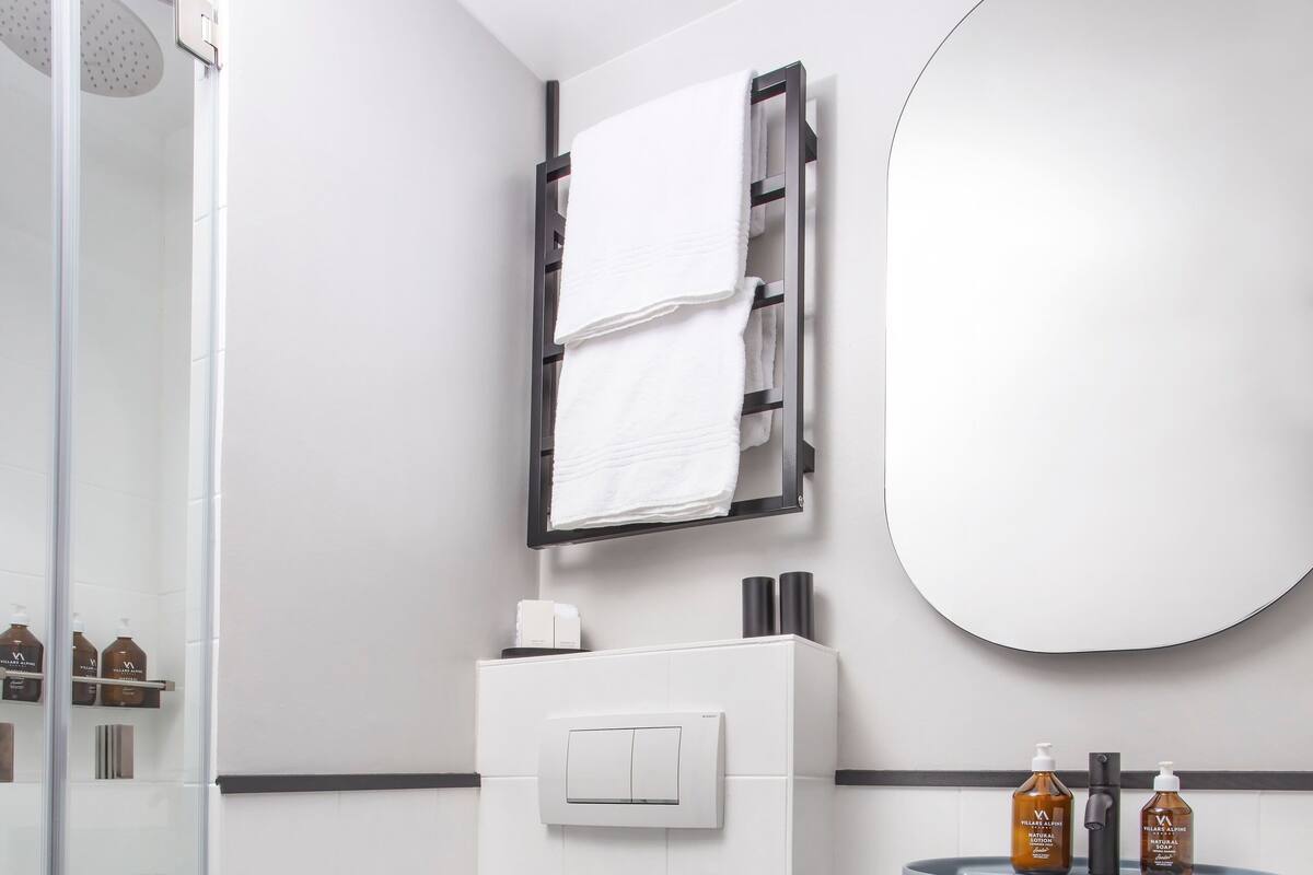 A modern bathroom with a toilet, bidet, and a sink with a towel rack.