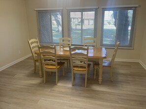 A dining area with a wooden table and chairs, large windows with blinds, and a light-colored floor. - Home Away from Home! Close to Everything! JU only 5 Mins Away!!! (Jacksonville)
