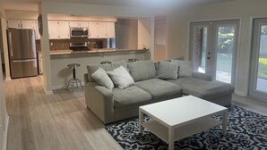Un salón moderno con un sofá seccional gris, una mesa de centro blanca y una alfombra estampada.
