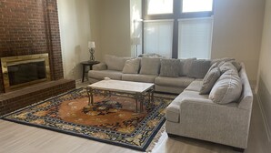 Una sala de estar con un sofá modular, una chimenea y una alfombra estampada.