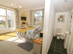 A bedroom with a bed, bedside table, lamp, and a TV.