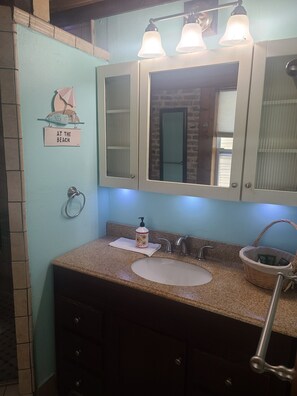 Een badkamer met een wastafel, spiegel en handdoekhouder.