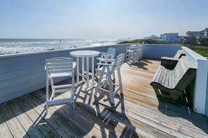Une terrasse en bois, agrémentée de mobilier d’extérieur blanc, avec vue sur l’océan.