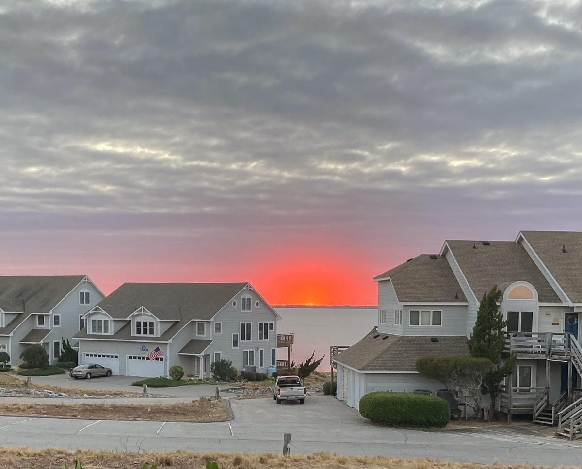 Una hilera de casas de un piso con vista al atardecer sobre el agua.