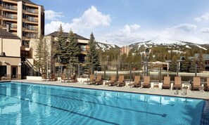 Ett poolområde vid hotellet med solstolar och en bergskedja i bakgrunden.