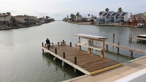 A wooden dock extending into calm water, with a small shelter and benches. - Cozy Clean Coastal Studio... Newly Remodeled! (Corpus Christi)