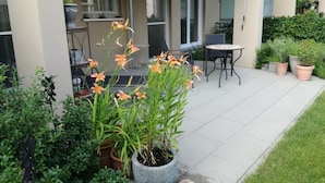 A patio with a table and chairs, potted plants, and a view of the building's exterior. - Luxurious apartment (2 rooms; 70 sqm; terrace; garden; air conditioning...) (Buggingen)