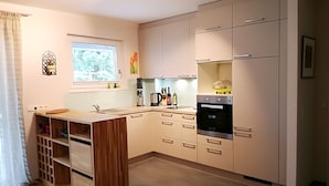 A modern kitchen with a wooden island, built-in appliances, and a window providing natural light. - Luxurious apartment (2 rooms; 70 sqm; terrace; garden; air conditioning...) (Buggingen)