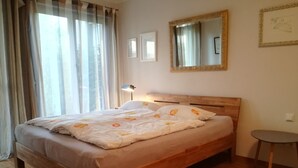 A neatly made bed with floral bedding, a wooden headboard, and a bedside lamp. - Luxurious apartment (2 rooms; 70 sqm; terrace; garden; air conditioning...) (Buggingen)