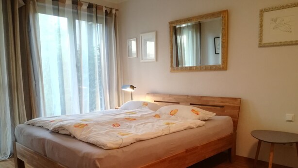 Una cama bien tendida con ropa de cama floral, un cabecero de madera y una lámpara de noche.