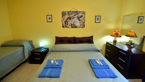 Ein Schlafzimmer mit zwei Betten, einem Nachttisch mit Lampe, einer Kommode und einem Wandbild.
