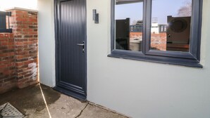 A dark blue door with a metal handle, a window with a black frame, and a brick wall. - Chalet 1 (Malton)