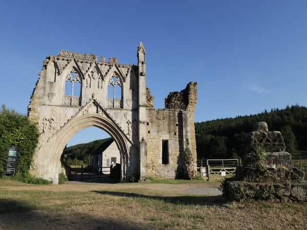 Un antiguo arco de piedra con intrincados grabados, que conduce a un edificio de piedra con una pequeña puerta.
