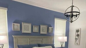 Un dormitorio con cama, mesitas de noche, una lámpara de araña y decoración en las paredes.