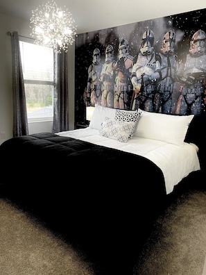 Une chambre à coucher avec un lit, un lustre, une fenêtre avec des rideaux et un mur orné d’une fresque sur le thème de l’espace.
