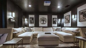 Una sala de estar moderna con un sofá modular, una mesa de centro y un televisor de pantalla plana montado en el techo.
