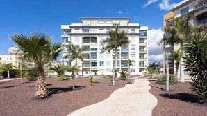 Un hotel moderno con un patio central, palmeras y un paseo empedrado.
