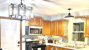 A kitchen with wooden cabinets, a stove, a microwave, and a sink. - Cheerful residential house with all yours needs. (St. Louis)