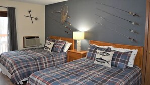 A room with two beds, a wall-mounted rack of fishing rods, and a lamp. - Birch Point Resort Condo #19 - Nelson Lake, Hayward (Hayward)