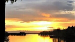 A calm lake at sunset with boats docked at the shore. - Birch Point Resort Condo #19 - Nelson Lake, Hayward (Hayward)