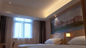 Habitación de hotel con dos camas, un cuadro en la pared, una ventana con cortinas y una silla.