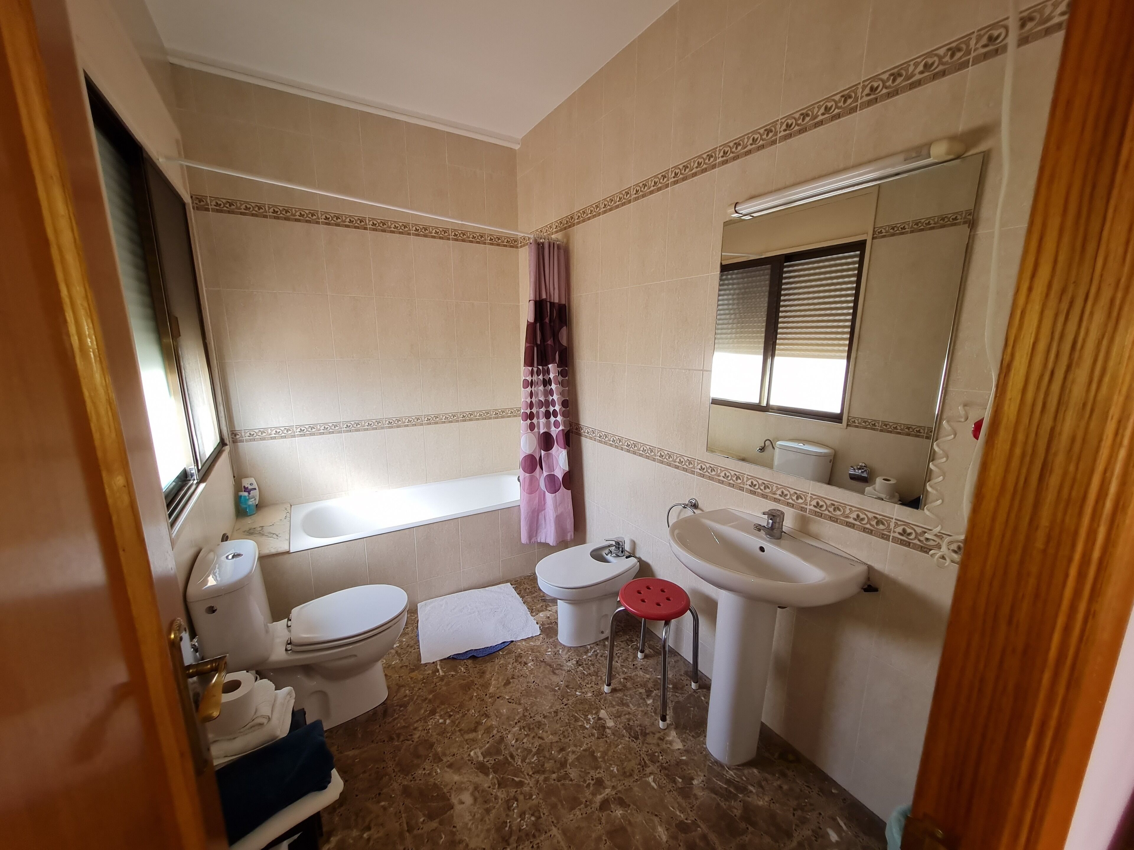 A bathroom with a toilet, sink, bathtub, and a shower curtain.