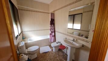 Un baño con inodoro, lavabo, bañera y cortina de ducha.