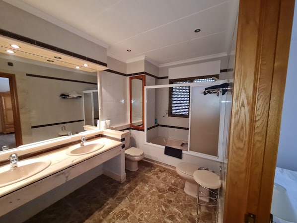 A modern bathroom with two sinks, a toilet, a shower, and a vanity with a mirror. - hotel bon lloc (Ulldecona)