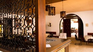 Zona de recepción con mostrador de madera, barandillas de metal ornamentadas y lámparas colgantes de estilo farol.