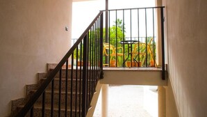 Una escalera con barandilla de metal que lleva a un balcón con sillas amarillas y una mesa.