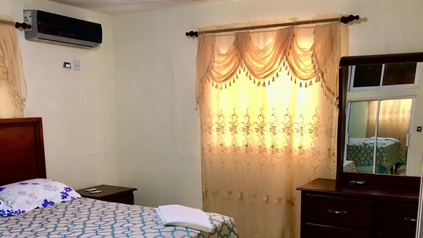 Une chambre à coucher comprenant un lit, une commode, un miroir et un appareil de climatisation.