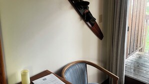 A room with a wooden desk, a chair, a ski on the wall, and a window with curtains.