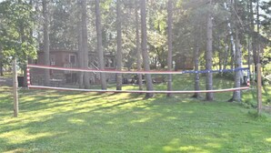 A volleyball net set up in a grassy area with trees in the background.