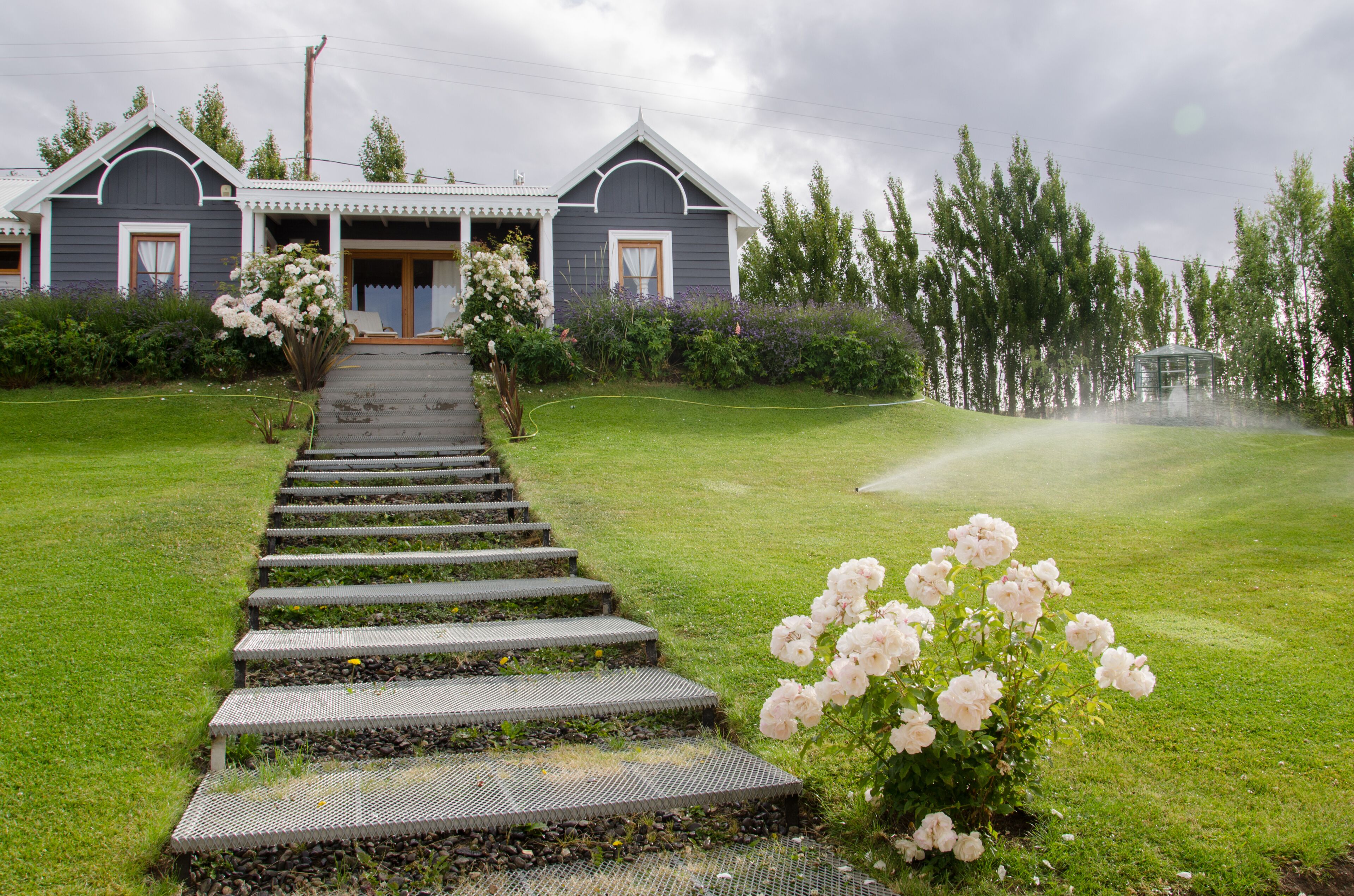 A house with a covered porch, a staircase leading to the entrance, and a lawn with flowers.
