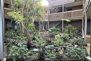 Un atrio de varios niveles con un jardín que presenta diversas plantas y una escalera central.