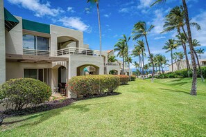 A resort with a two-story building, a well-maintained lawn, and tall palm trees. - Palms at Wailea 703 - Modern Renovation, Prime Location, Full AC, Close to Pool! (Kihei)