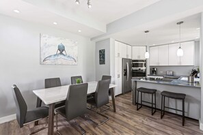 Una cocina moderna con una isla central, taburetes de bar y una mesa de comedor con sillas.