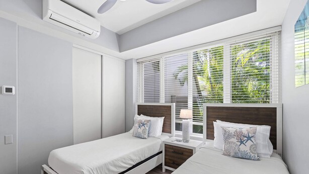 A modern bedroom with two beds, a nightstand, a lamp, and a window with blinds. - Palms at Wailea 703 - Modern Renovation, Prime Location, Full AC, Close to Pool! (Kihei)