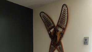 A room with a dark wall, a wooden chair, and a wall-mounted decorative piece resembling a bird or insect.