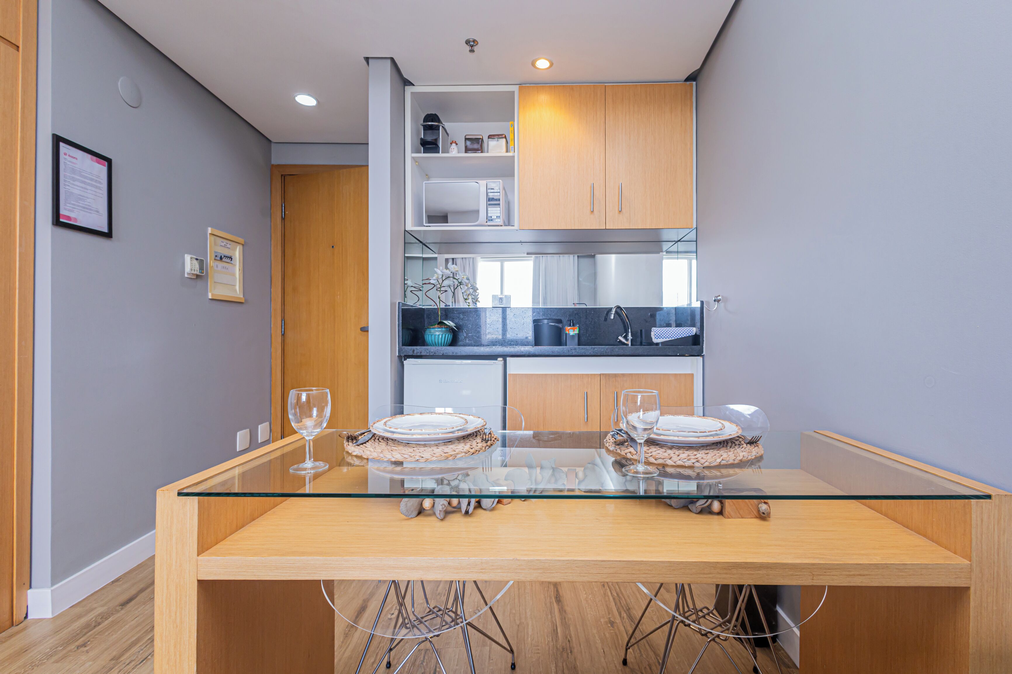 Una cucina moderna con mobili in legno, un forno a microonde integrato e un tavolo da pranzo in vetro con due sedie.