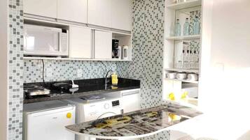 Una cocina compacta con microondas, estufa y lavamanos.